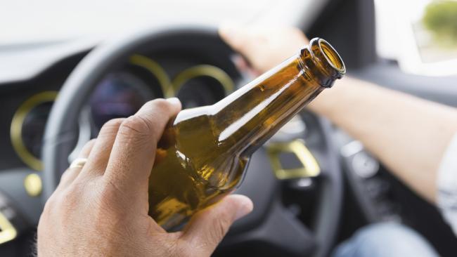Image of an open bottle in car of a drunk driver about to cause a car accident