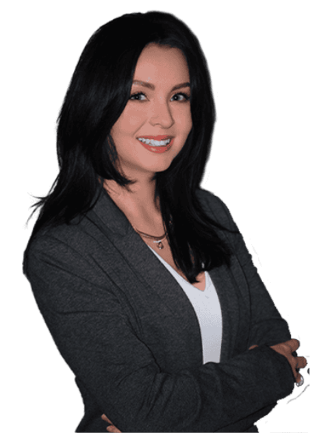 Woman with long dark hair wearing a gray blazer and white top, smiling with arms crossed, posed against a plain light background.