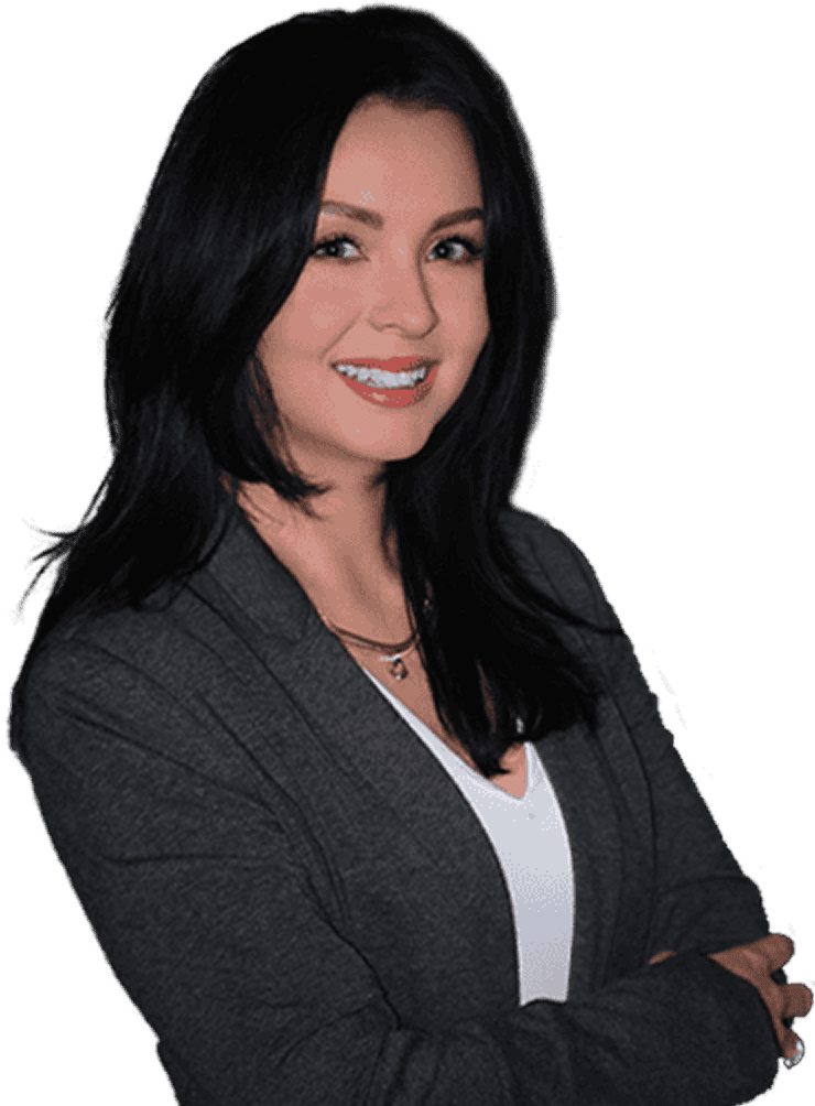 Woman with long dark hair wearing a dark blazer and white top, smiling, standing with arms crossed against a white background.