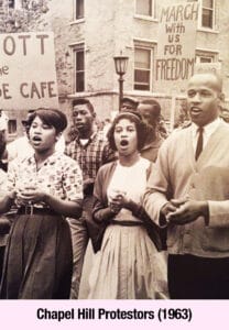 A group of young Black men and women, inspired by empowerment, protest segregation in Chapel Hill in 1963, holding signs including one that reads “MARCH WITH US FOR FREEDOM.”.
