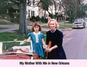 A woman and a young girl stand beside a red convertible parked on a suburban street; radiating empowerment, they evoke the spirit of a modern Southern Belle amid houses and a vintage car in the background.