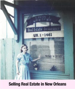 A woman exudes empowerment as she stands before a real estate and insurance office in New Orleans, with signage for Louis Herbert and notary services visible on the window—a modern Southern Belle amid historic charm.
