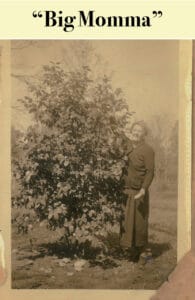 Sepia photo of an older woman standing outdoors next to a large leafy bush, with the words "Big Momma" written above, evoking memories of Louisiana's rich flora and the enduring legacy of Virginia Settlers.