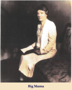 A woman in a light-colored dress sits on a cushioned bench, holding an open book in her lap, with the caption "Big Mama" below the image—a scene reminiscent of the journeys from Scotland to Louisiana.