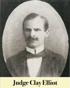 Black and white portrait of a man with a mustache in a suit and bow tie, labeled "Judge Clay Elliot," an esteemed figure among Louisiana's early Virginia Settlers.