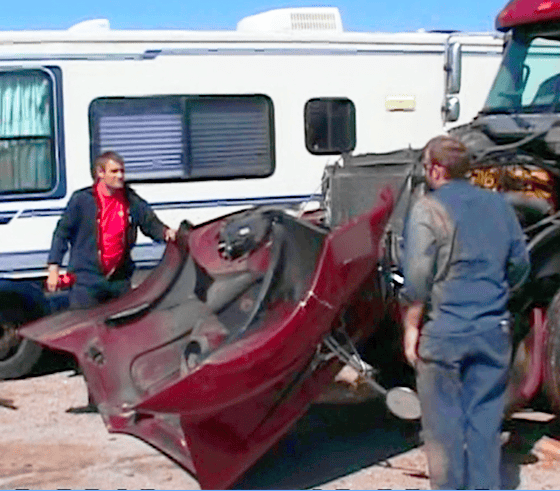 Two men stand near a damaged red car part wedged into the front of a truck, with an RV parked in the background—an incident where Truck Accident Lawyers in Owensboro KY could help.